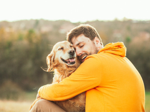 Man holding his dog's head and smiling